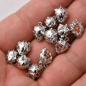 Macro shot of 14K gold-plated strawberry charms with red zircon stones for DIY jewelry