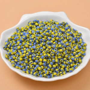 Macro view of blue and yellow candy-colored striped seed beads in a white shell dish