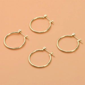 Dettaglio macro di quattro orecchini a cerchio tondi placcati oro 14k con chiusura a cerniera