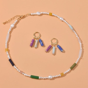 Detailed macro of colorful stone cylinder beads and pearls jewelry set on orange surface