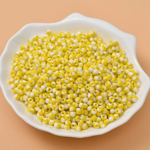 DIY yellow and white candy striped seed beads for jewelry making in a shell tray
