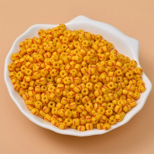 Macro shot of candy-colored striped yellow beads in a decorative white shell bowl