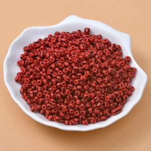 Macro shot of red candy striped seed beads for DIY jewelry making in a shell dish