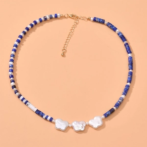 Detailed view of blue stone cylinder beads and white pearl necklace with gold clasp