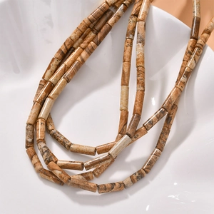Macro view of cylindrical picture jasper beads with natural textures on ceramic plate