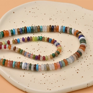 Macro shot of colorful flat natural stone beads arranged on a ceramic tray for DIY jewelry