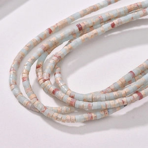 Macro detail of natural stone cylinder beads with blue and beige marble texture for DIY jewelry