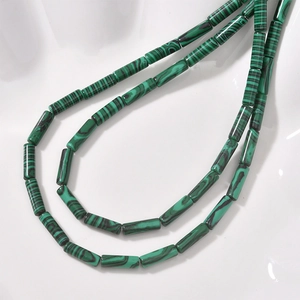 Macro shot of malachite green cylindrical stone beads showing striped patterns and texture