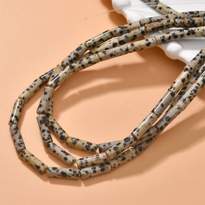 Detailed view of cylindrical Dalmatian Jasper stone beads with natural black spots on orange base
