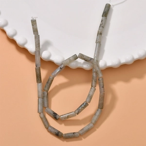 Close-up of cylindrical labradorite stone beads with grey texture and blue flashes