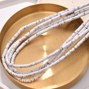 Detailed view of layered white turquoise disc beads in a decorative golden tray
