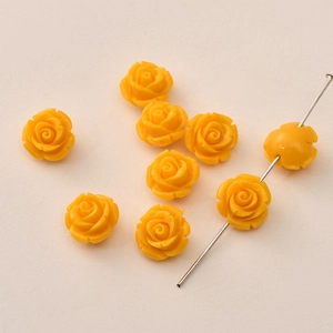 Close-up of bright yellow 12mm rose flower beads with a metal pin showing center hole
