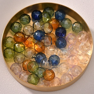 Macro shot of faceted hollow glass beads in mixed colors on a gold metal tray