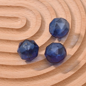 Close-up of deep blue faceted glass beads for DIY jewelry making on wooden tray