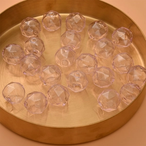 Macro shot of pink faceted hollow glass beads in a golden tray for DIY jewelry making