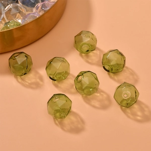 Macro detail of faceted green glass beads for DIY jewelry making on warm orange background