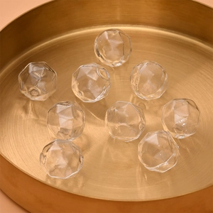 Detail shot of multi-faceted hollow glass bubble beads in a gold metal tray