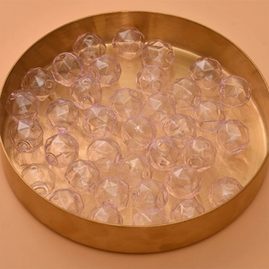 Macro view of light purple faceted glass beads in a gold tray for DIY jewelry making