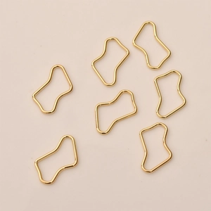 Nahaufnahme unregelmäßiger goldener Metallanhänger für DIY-Schmuck und Bastelarbeiten