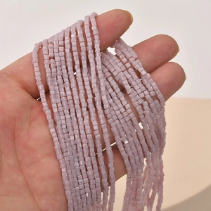 Close-up of hand holding 2mm light purple cube glass beads for DIY jewelry making