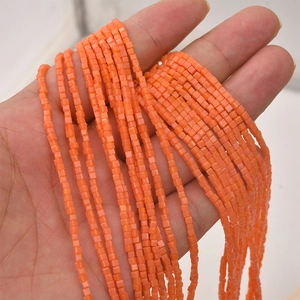 Close-up of 2mm bright orange square glass beads held in hand for DIY jewelry making