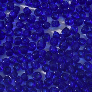 Makroaufnahme von 4 mm dunkelblauen transparenten Glasperlen auf weißem Stoffgrund