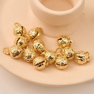 Close-up of 14K gold plated hollow bell charms with celestial star and moon patterns