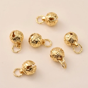 Macro detail of 14K gold plated bell charms with intricate celestial swirl engravings