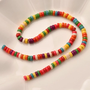 Close-up of colorful round disk spacer beads arranged in a S-curve on white ceramic tray