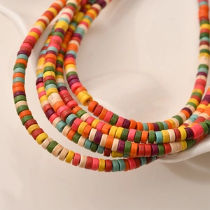 Colorful heishi bead necklaces in a mixed rainbow pattern displayed on a white ceramic plate