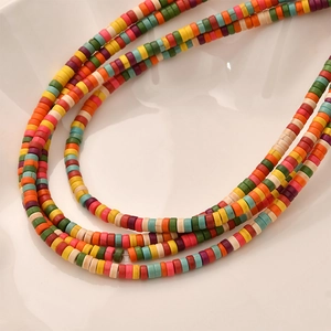 Macro view of multi-layered colorful heishi clay bead necklace on a wavy white tray