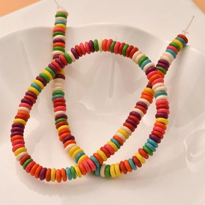 Macro shot of colorful flat disc spacer beads in a ceramic bowl for DIY jewelry making