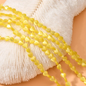 Detailed view of yellow cat's eye heart-shaped beads for DIY jewelry making
