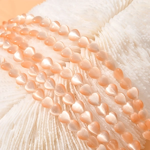 8mm peach heart cat eye stone beads for DIY jewelry making displayed on a white coral base