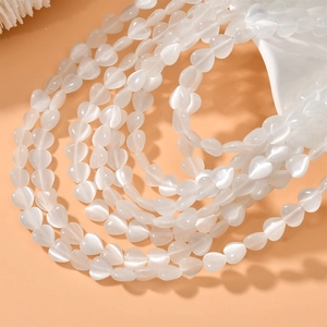 Macro detail of 8mm heart-shaped white cat eye opal beads for DIY jewelry making