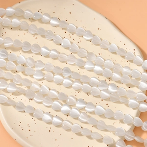 Detail of 8mm heart-shaped white cat eye beads for DIY jewelry making and craft projects