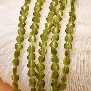 Macro detail of 8mm green heart cat-eye stone beads with polished glossy finish