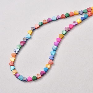 Macro shot of colorful heart-shaped natural shell beads with iridescent luster for DIY jewelry