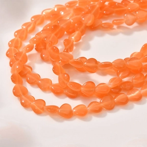 Close-up of 8mm orange heart cat eye beads showing internal reflective texture for DIY jewelry