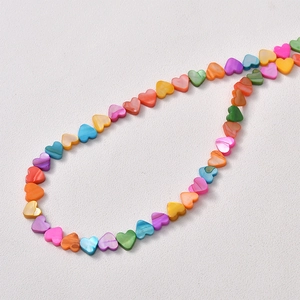Flat lay of colorful heart-shaped shell beads for DIY jewelry making accessories