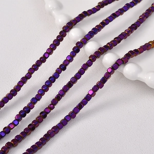 Macro shot of 3x3mm purple metallic hematite cube beads on a wavy ceramic display
