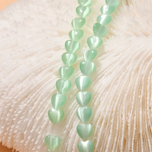 Macro view of light green cat eye heart beads for DIY jewelry making and crafting