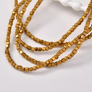 Close-up of small golden cube beads showing metallic texture and polished finish