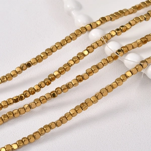 Macro view of polished golden cube beads on strings for DIY jewelry making