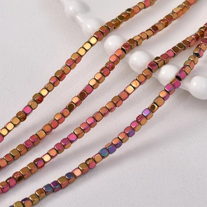 Macro shot of 3mm iridescent square hematite beads with polished metallic finish