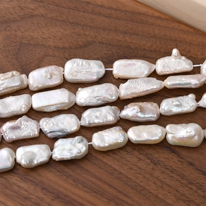 Irregular baroque freshwater pearl strands with high luster on a dark wood background