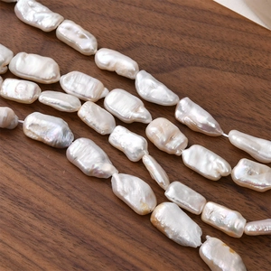 Macro shot of irregular baroque freshwater pearls on a dark walnut wood surface