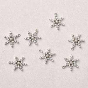 Macro detail of snowflake jewelry pendants with pearls and zircon inlay for DIY crafting