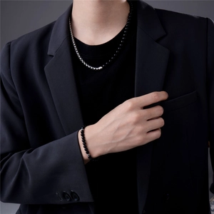 Detail von Schmuckset für Herren mit schwarzen Perlenarmband und silberfarbener Halskette