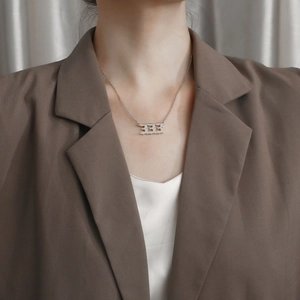 Collana minimalista in acciaio argentato con ciondolo numero 333 orizzontale su modella donna